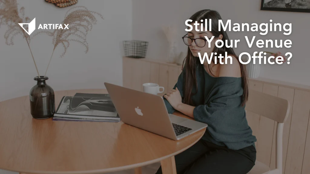 A woman sitting at a round wooden table working on a laptop, with a notebook, vase, and coffee cup nearby, accompanied by the text “Still Managing Your Venue With Office?”