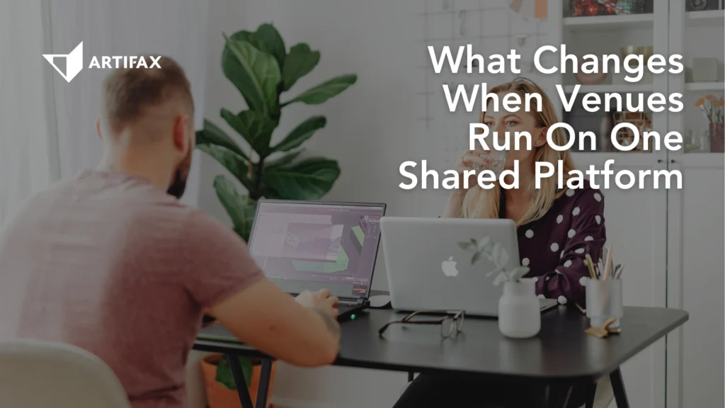 Two colleagues working at a shared table on their laptops, with Artifax branding and the text What Changes When Venues Run On One Shared Platform