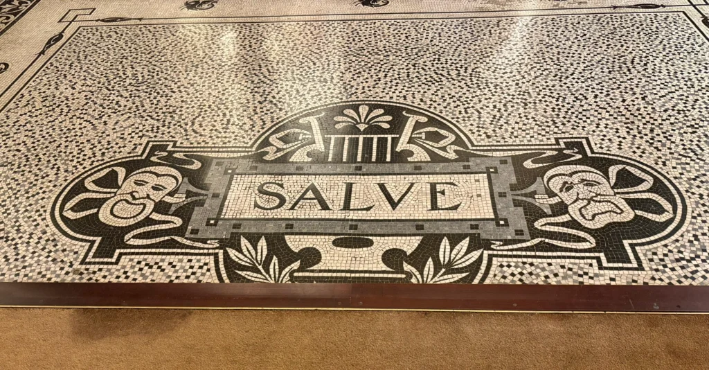 Mosaic floor with the word “Salve” set into an ornate black-and-white tile design.