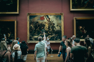 Tourists in a museum observing a large historic painting on a red wall.