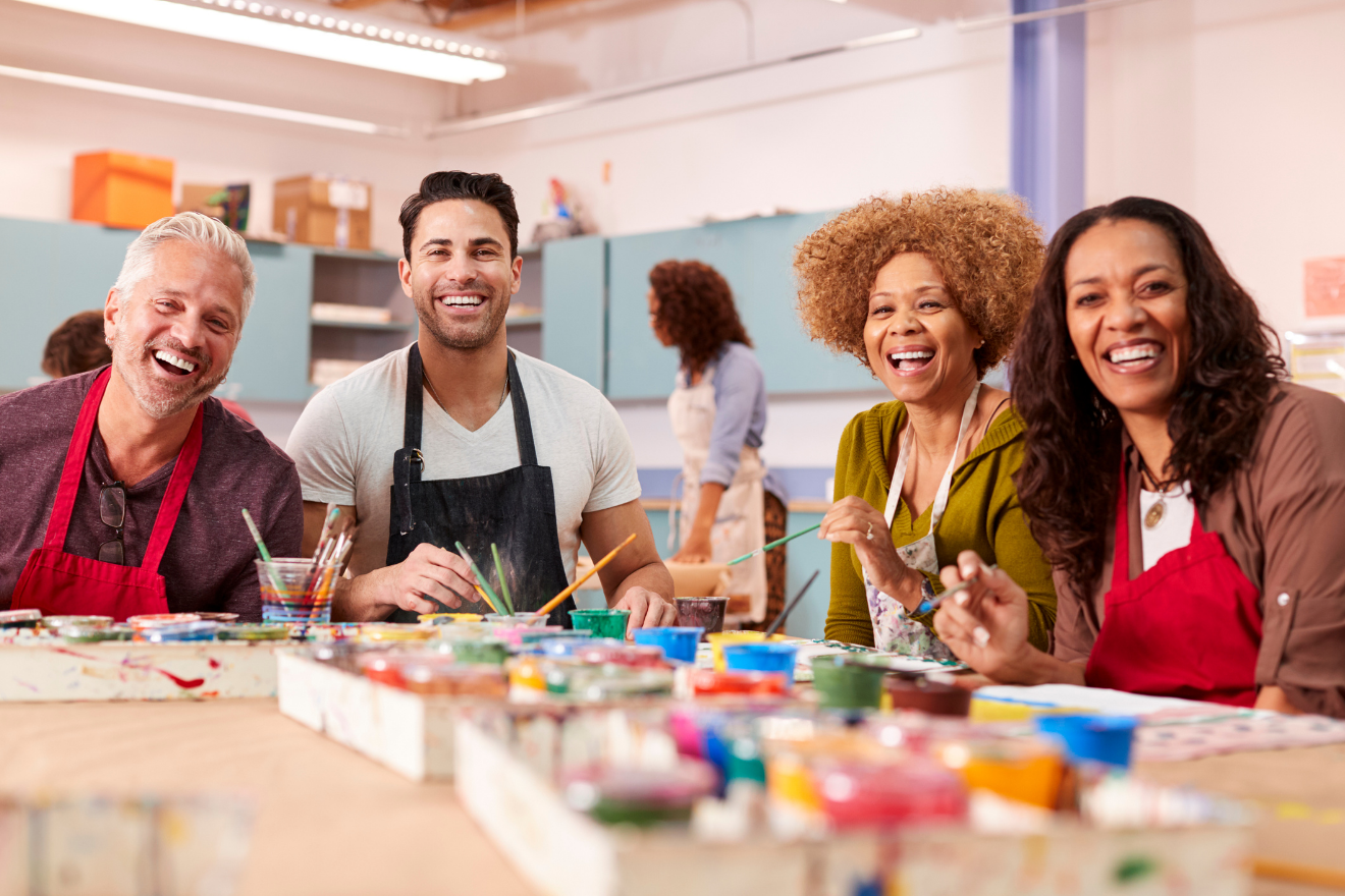 Group of smiling adults participating in a painting class at a community arts centre.