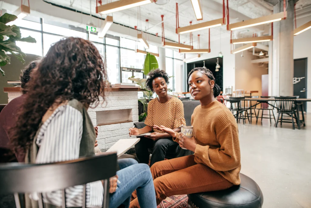 Small group of people seated in a modern office space having a casual discussion.