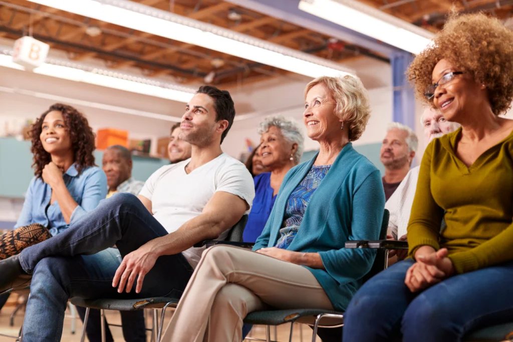 Diverse community audience seated and smiling during a presentation.