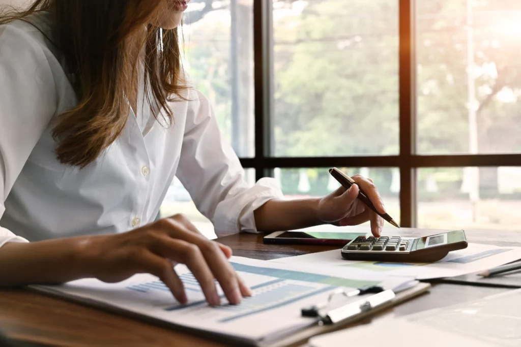 Person using a calculator and pen while reviewing financial documents at a desk