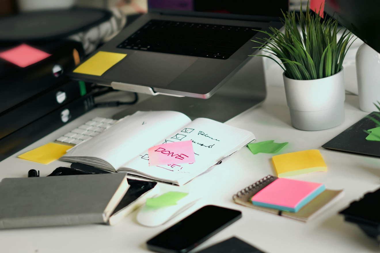 Organised workspace with planner, post-it notes, and a laptop.
