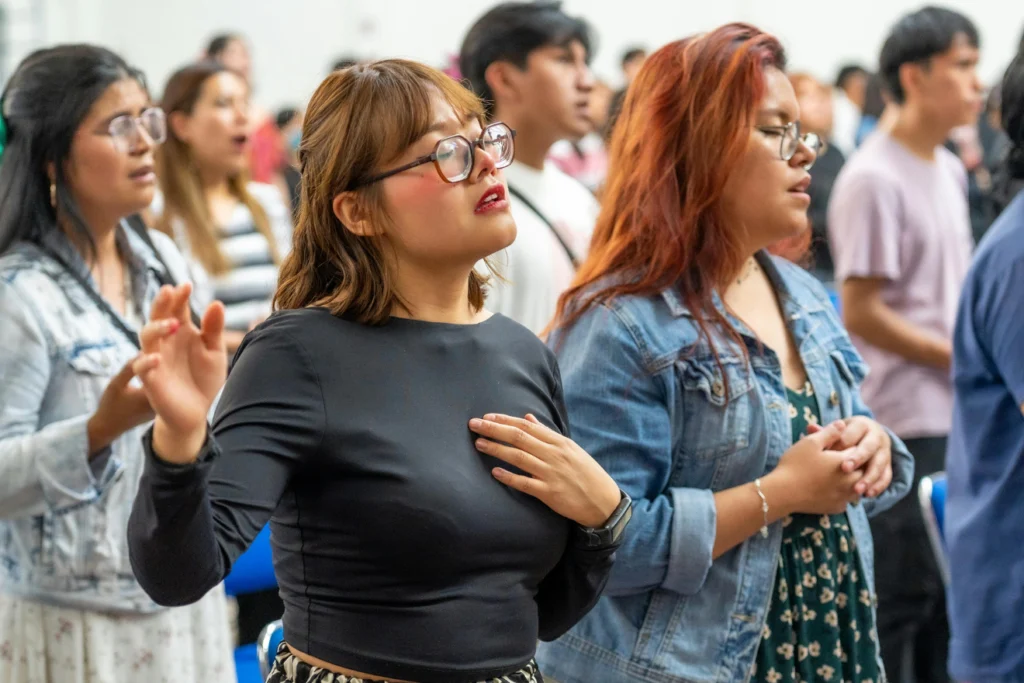 Group of people in a congregation singing during a worship service.