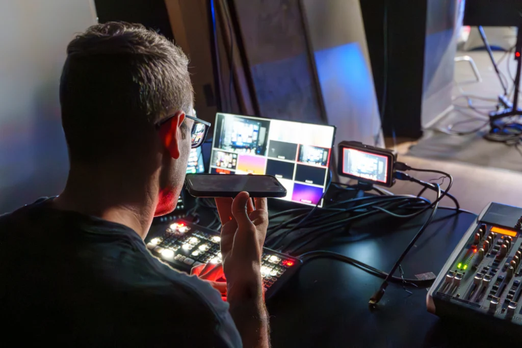 A technician monitoring multiple video feeds at a live production control desk.