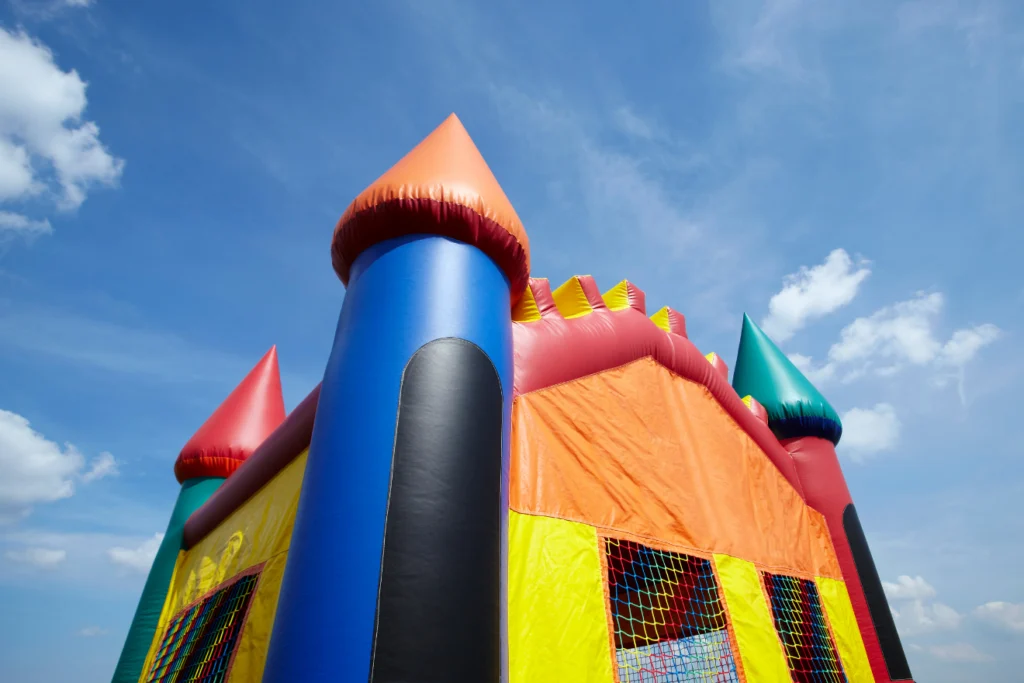 Bright inflatable bounce house with castle towers against a blue sky. Bright inflatable bounce house with castle towers against a blue sky.