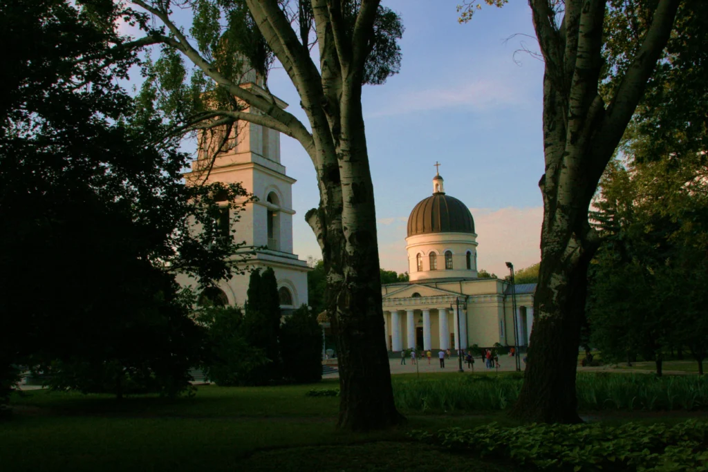 Orthodox cathedral and bell tower surrounded by trees at dusk.