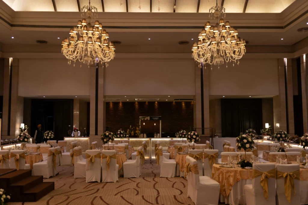 Elegant ballroom set for a formal event with chandeliers and floral centrepieces.