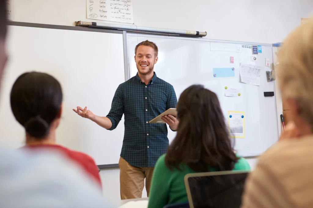 Teacher presenting to a class of adult learners using a whiteboard.
