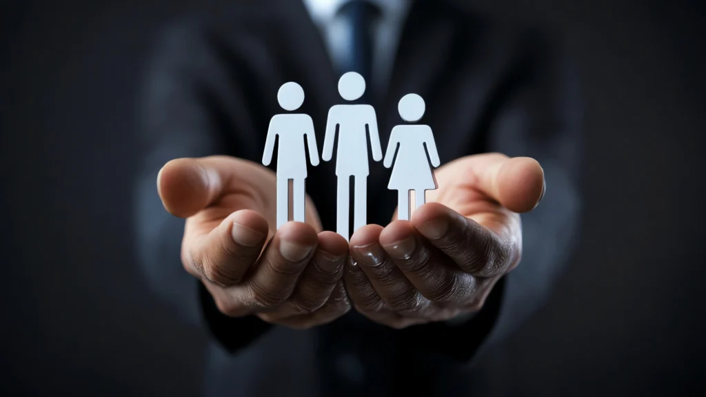 Hands holding three paper cut-out figures symbolizing people or a team.