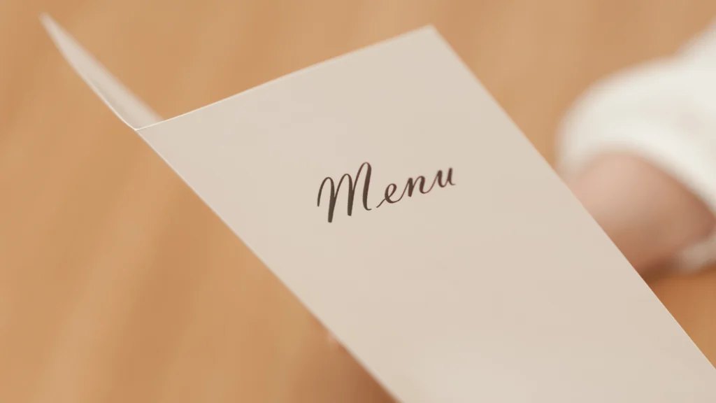 Close-up of a minimalist restaurant menu with the word “Menu” on the cover.
