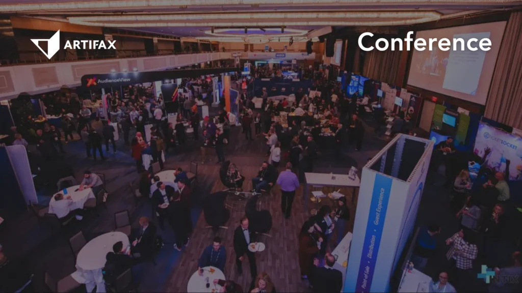 A bustling conference exhibition floor with multiple booths, including AudienceView and TicketSocket, filled with attendees networking and exploring solutions. Artifax logo and "Conference" text overlay included.