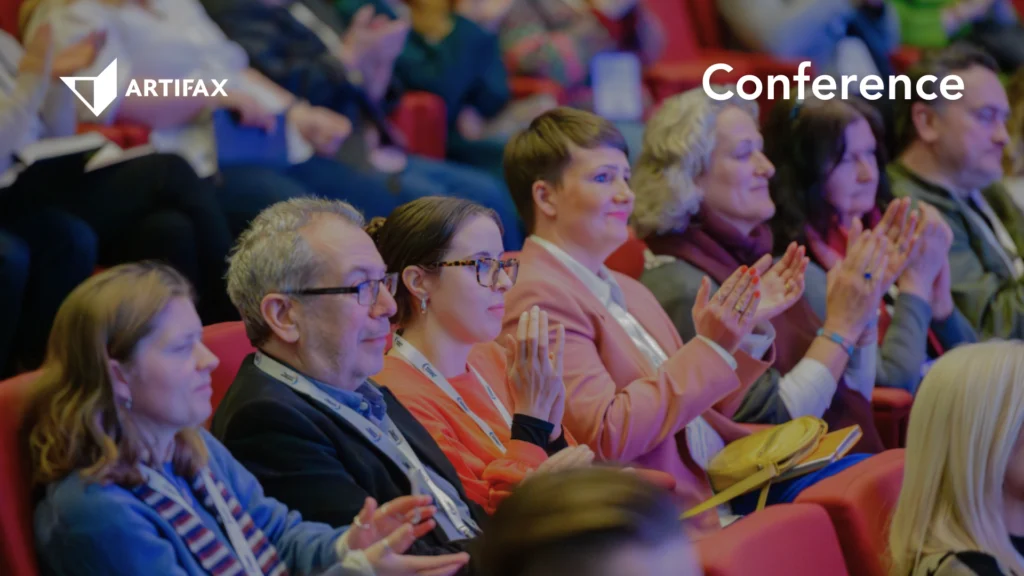 A seated audience applauding during a conference session, with the Artifax logo and the word "Conference" overlaid.